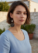 Paniery African statement earrings with cowrie shells and dark wood discs, handcrafted from recycled brass and natural materials.