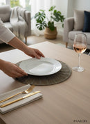 Paniery beaded placemat with delicate beadwork in a neutral tone, set on a wooden table with a white plate and gold cutlery.