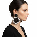Paniery black and white handwoven spiral statement earrings on a model.