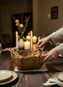 Paniery hand-carved wooden sun bowl with braided serving spoons, natural wood grain, lotus-inspired shape, on a dark wood table with candles.