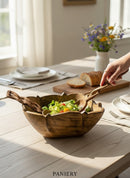 Paniery hand-carved wooden sun bowl with salad and serving utensils, featuring organic design and natural wood grain.