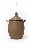 Paniery luxury handwoven laundry basket in natural fibers with black leather trim and handles. Oval shape with a domed lid.