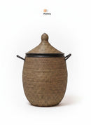 Paniery luxury handwoven laundry basket in natural fibers with black leather trim and handles. Oval shape with a domed lid.