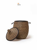Paniery luxury handwoven laundry basket in natural fibers with black leather trim and handles. Lid is open.