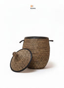 Paniery luxury handwoven laundry basket in natural fibers with black leather trim and handles. Lid is open.