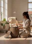 Paniery luxury handwoven laundry basket in brown and black with leather trim, filled with towels and toiletries.