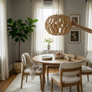 Paniery handwoven natural raffia pendant lampshade with a sculptural, geometric design, casting a warm glow in a dining room.