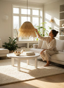 Paniery handwoven natural raffia lampshade with fringe detail, creating a warm, diffused light in a modern living room.