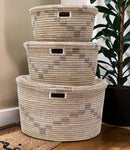 Paniery handwoven Senegalese storage baskets made from recycled plastic and seagrass. Natural beige and grey woven pattern with cut-out handles. Stacked set.