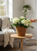Paniery handwoven mini vase from Rwanda, made of natural fibers, holding white hydrangeas and eucalyptus.