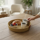 Paniery natural woven tray with leather handles, holding bread, berries, and coffee cups on a wooden table.