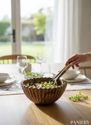 Paniery handcrafted olive wood salad bowl with unique grain and fluted rim, shown with salad and decorative serving spoons.
