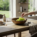 Paniery handcrafted olive wood bowl with scalloped edge, filled with green grapes, on a rustic wooden table.