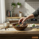 Paniery handcrafted dark brown olive wood serving bowl with scalloped edge, filled with blueberries, almonds, and mint leaves.