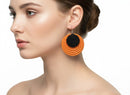 Paniery orange and black handwoven spiral statement earrings with a textured finish, worn by a model.