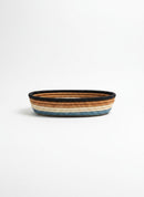 Paniery oval handwoven basket with blue, beige, brown, and black stripes. Made from natural fibers.