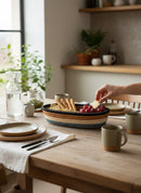 Paniery oval handwoven basket with blue, tan, and black stripes, filled with crackers and grapes on a wooden table.