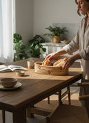 Paniery oval handwoven basket made of natural fibers with red stripe detail, holding fresh bread on a wooden table.