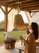 Paniery handwoven natural raffia lampshade with fringe detail, hanging outdoors.