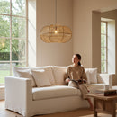 Paniery handwoven natural raffia pendant lampshade with an organic shape, casting diffused light in a living room.
