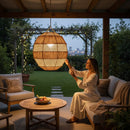 Paniery handwoven natural raffia lampshade with a sculptural design, creating ambient light on an outdoor patio.