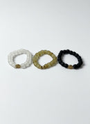 Paniery African Heritage recycled glass bracelets in white, beige, and black. Minimalist, unisex design with unique spiral charm.
