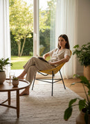 Paniery Signature Solis chair in yellow, handwoven from recycled fishing lines, with a woman sitting and reading.