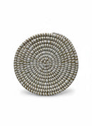 Paniery handwoven white natural fiber coaster with a concentric spiral pattern, adding an elegant touch to table settings.