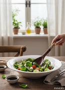Paniery hand-carved wooden spoon with colourful Maasai beadwork, serving a fresh salad.