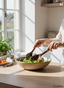 Paniery hand-carved wooden salad servers with colorful Maasai beadwork handles, serving a salad.