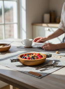 Paniery handcrafted wooden serving bowl with handles filled with granola, strawberries, and blueberries. Natural wood finish.