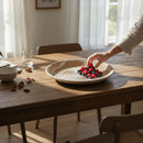 Paniery hand places berries in a beige and cream woven wall basket with spiral pattern. Natural fibers, bohemian style.